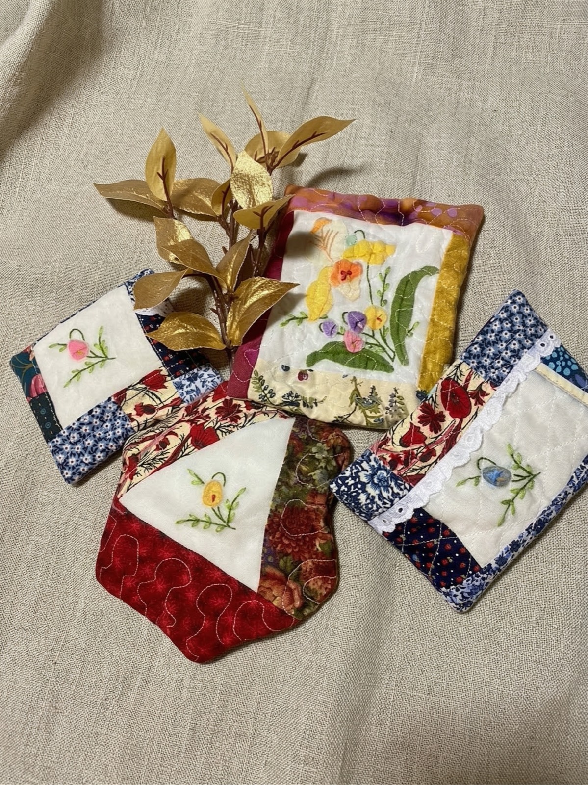 Collection of small embroidered quilted pouches with hand-embroidered floral motifs arranged with gold leaves